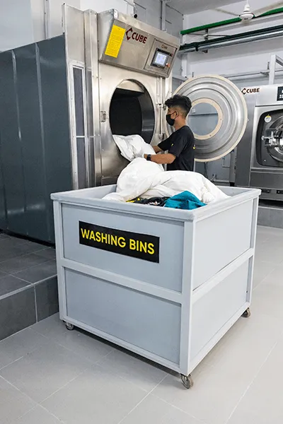 Worker loading clothes into a washing machine.