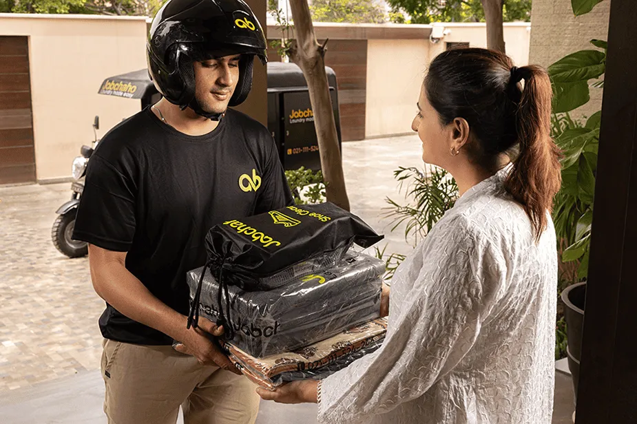 Jab chaho rider handing over cleaned clothes to a customer at their doorstep.