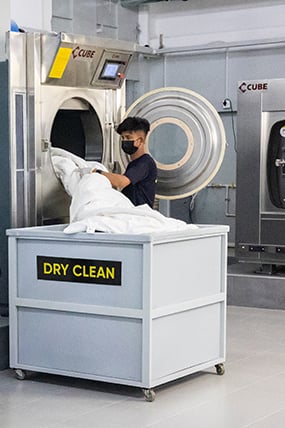 Worker loading clothes into a washing machine.